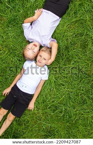 Children lie on the grass and look at the sky.  A boy and a girl of six years old, of European appearance, lie on green gas in different poses.