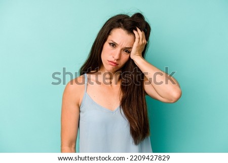 Young caucasian woman isolated on blue background tired and very sleepy keeping hand on head.