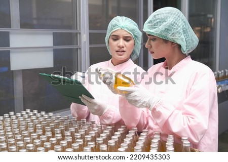South Asia woman factory worker or woman expert quality staff is checking bottles line for beverage Royalty-Free Stock Photo #2209435303
