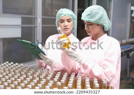 South Asia woman factory worker or woman expert quality staff is checking bottles line for beverage