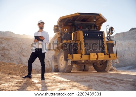 Smart man in glasses and in uniform is working in the quarry at daytime. Royalty-Free Stock Photo #2209439501