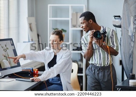 Portrait of two photographers working as team on product photoshoot in studio