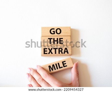 Go the extra mile symbol. Wooden blocks with words Go the extra mile. Beautiful white background. Businessman hand. Business and Go the extra mile concept. Copy space.