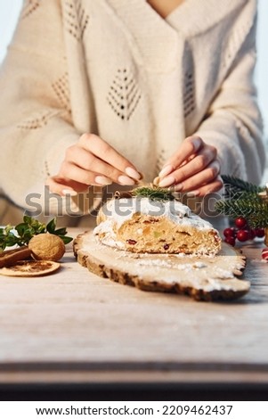 Woman standing and decorating stollen that is on the holiday christmas table.