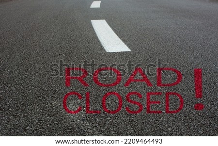empty asphalt road and white road line, "road closed" written on the road