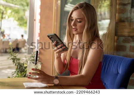 Beautiful woman texting on her smartphone in a cafe bar