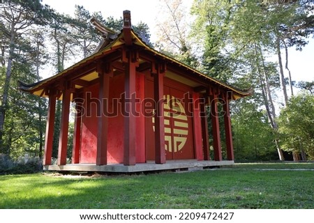 red asian pagoda temple with yellow symbol ans sunlight , Vincennes tropical agronomy garden 