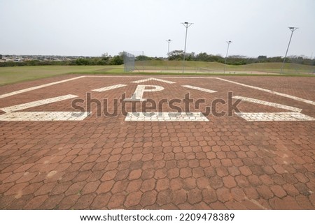 Heliport. A large area with a special symbol in the center for helicopter landing. Private helipad in a green field in a luxury resort. Constructed with stones and white paint marking