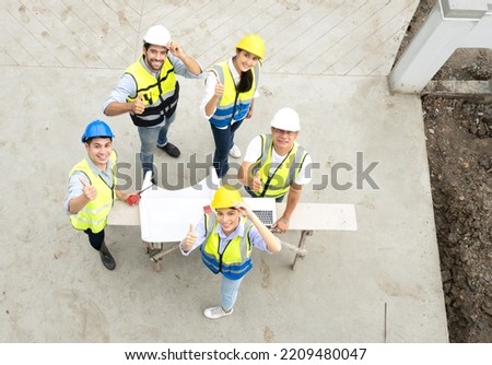 Engineer man and architect teamwork wear safety helmet meeting at construction site with blueprint for engineering project design, top view. High angle view of construction workers brainstorming.