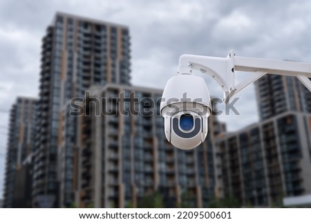Panoramic view of CCTV surveillance camera with blurred apartment building background with copy space for background banner