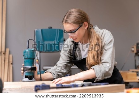Portrait of a female carpenter using tools for making furniture in a furniture factory. with modern tools