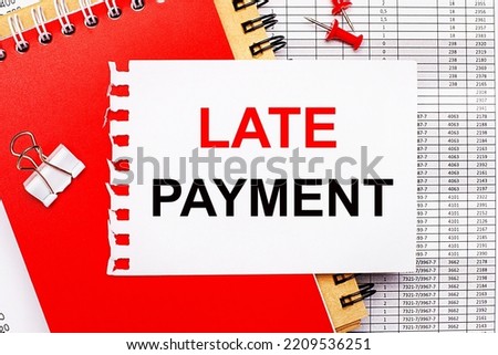 Against the background of the reports, there are red and brown notepads, a white paper clip, red buttons and a white sheet of paper with the text LATE PAYMENT. Business concept
