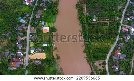Aerial view of the river flowing after heavy rain and flooding of fields in rural villages. Top view of agricultural areas affected by rainy season floods. Climate change concept