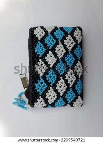 Handcrafted beaded purse of the Kalimantan Dayak tribe. diagonal pattern, colored white and light blue.