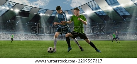 Goalmouth scramble. Two male soccer, football players dribbling ball at the stadium during sport match at crowded stadium. Sport competition. Action, motion, energy and dynamic concept.