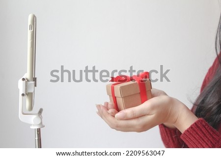 Girl takes a selfie with a gift box,  Selective focus. woman holding present and talk on VIDEO conference.