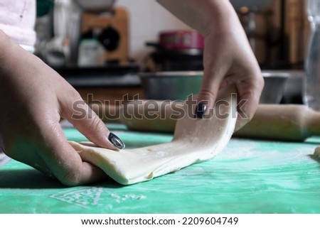 A woman prepares a piece of dough for rolling with a rolling pin. A woman prepares dough for rolling and baking