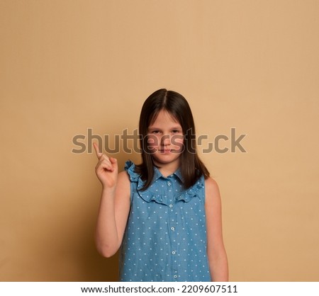 dark-haired girl 9-12 years old in a blue dress on a beige background