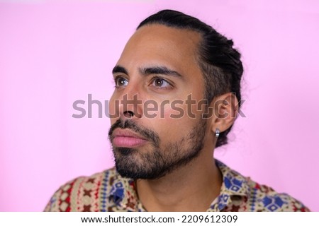 Brazilian man with hair tied paying attention over pink background. Colored Shirt. Royalty-Free Stock Photo #2209612309