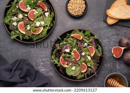 Food photography of salad with goat cheese, figs, leaves, pine nuts, toast, honey