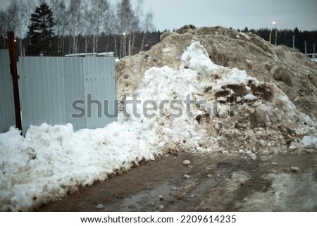 Fence is covered with snow. Removed snow to side of road. Industrial area after snowfall.