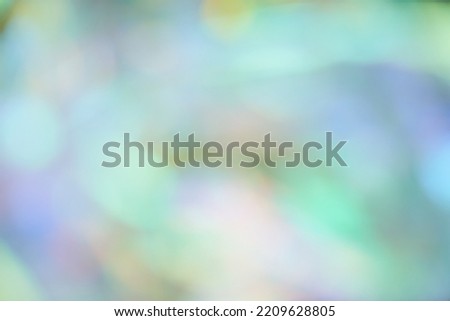 Unfocused holographic colors of mother-of-pearl foil. Blurry holographic abstract background in blue tones. Holographic iridescent abstract background made of rainbow foil. High quality photo