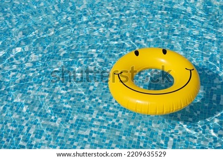 Yellow rubber ring floats in a pool of turquoise water. Clear and sunny weather.