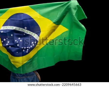 Person holds the Brazil flag in the wind, cut out and isolated from the background. Brazilian green and yellow patriotism.