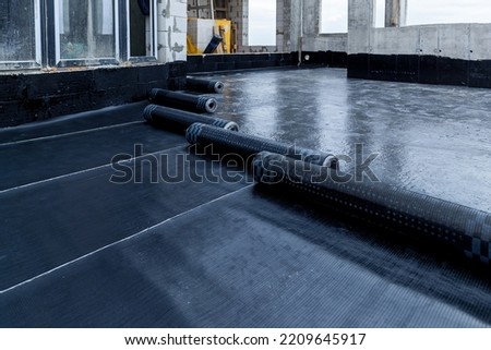 Laying and installation of roofing, bituminous waterproofing of an apartment building. Rolled roofing waterproofing of concrete slabs of stylobate. Heating and melting of bituminous roofing material. Royalty-Free Stock Photo #2209645917