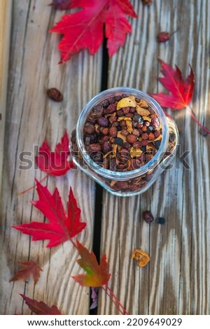 Berry and fruit tea in a glass jar, close-up with autumn leaves in the background. Dried apples, berries and cherries 