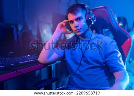 Streamer young man rejoices in victory professional gamer playing online games computer with headphones. Concept esport, neon color soft focus.