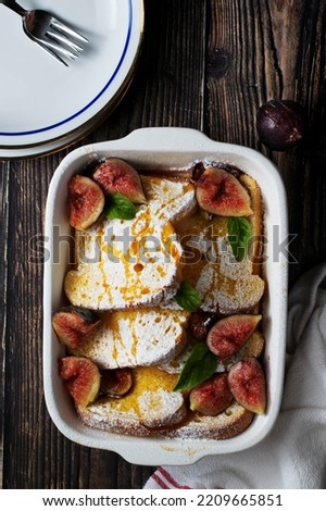 Baked french toast with figs, powder sugar and honey. Wooden bakcground