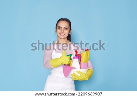 woman in gloves holding bucket of detergents and showing Ok gesture