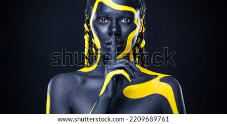 The Art Face. Black and yellow body paint on african woman. Abstract creative portrait. Bright fashion makeup on the girl.