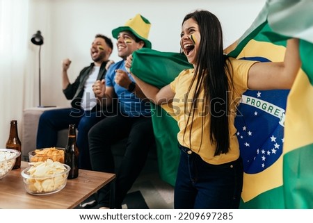 Football fans friends watching Brazil national team in live soccer match on TV at home Royalty-Free Stock Photo #2209697285