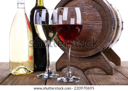 Wine in goblets and in bottles and wooden barrel on wooden table on white background