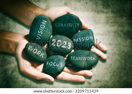 Closeup of unknown man holding pebbles of success future and 2023 number with wooden background