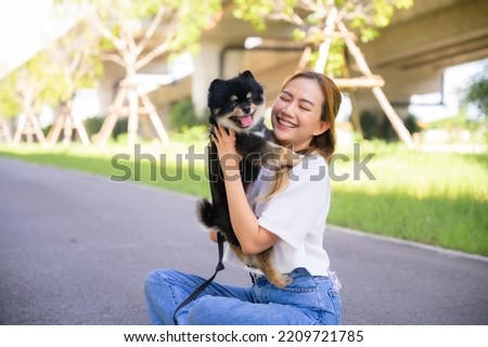 Happy young asian woman playing and sitting on road in the park with her dog. Pet lover concept Royalty-Free Stock Photo #2209721785