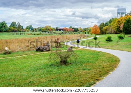 A person walking on the trail in Arboretum in Lexington, Kentucky in fall Royalty-Free Stock Photo #2209735253