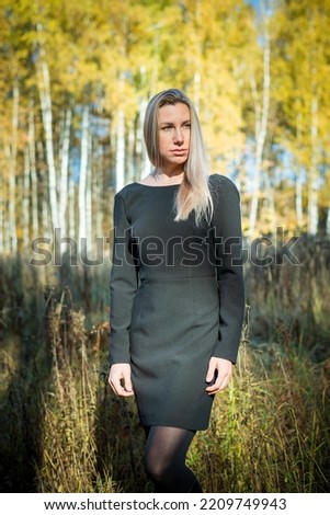 A girl in a black short dress walks on a beautiful autumn day in the park. Autumn Park.