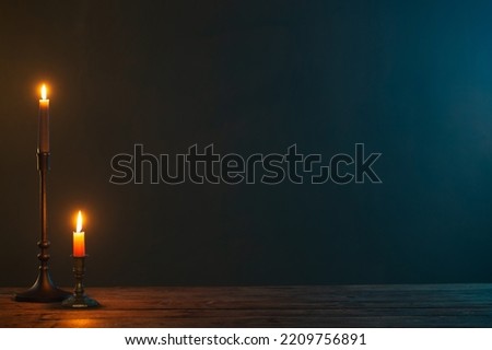 burning candles in vintage candlesticks on dark background Royalty-Free Stock Photo #2209756891