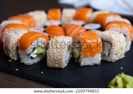 Delicious fresh sushi roll set on a black board. Sushi roll with rice, cream chees, red fish, salmon. Sushi menu. Japanese kitchen, restaurant. Seafood, asian food