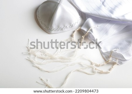 Prayer shawl tallit and kippah (religious hat). Jewish national and religious tallith katan - in the form of a cape with brushes. Still Life of Jewish symbols for Sukkot, shabbat, rosh hashanah. Royalty-Free Stock Photo #2209804473