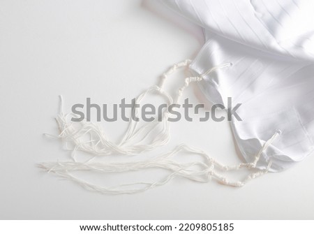 Tallit katan, background. Jewish national and religious tallith katan - in the form of a cape with brushes. Theme of traditions, jewish ritual object. Jewish holiday of Sukkot, shabbat, rosh hashanah. Royalty-Free Stock Photo #2209805185