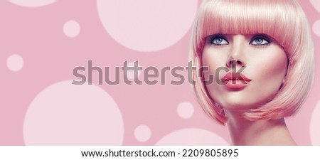 Beauty Fashion Model Portrait pink hair color. Bob Short Haircut. Fringe Hairstyle. Hairdressing. Beautiful Glamour Girl with Short blonde hair. Dyed hair, perfect makeup. Over pink background Royalty-Free Stock Photo #2209805895