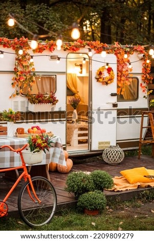 The campsite is decorated in autumn colors. An orange bicycle stands near the trailer