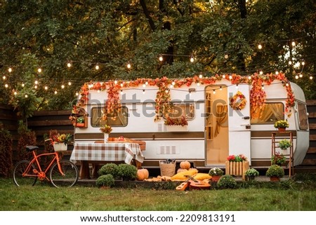 Camping season autumn. Photo studio. Trailer on the background of the forest. Bicycle on the background of the trailer.