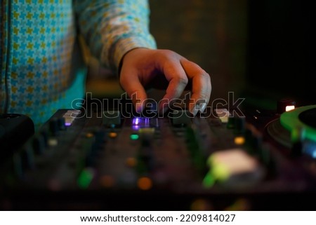 Hip hop dj plays music with sound mixer. Hand of disc jockey on cross fader knob. Professional disk jokey mixing musical tracks on party in night club