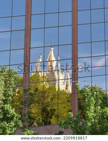 White church towers mirrored on the facade of a modern glass building. Salt Lake City, Utah, USA