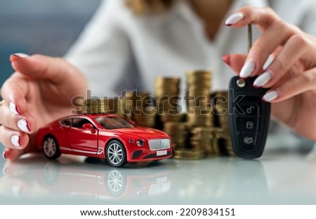 woman's hands hug a car model on a stack of dollars on a glass table. the concept of financing and loans. saving money